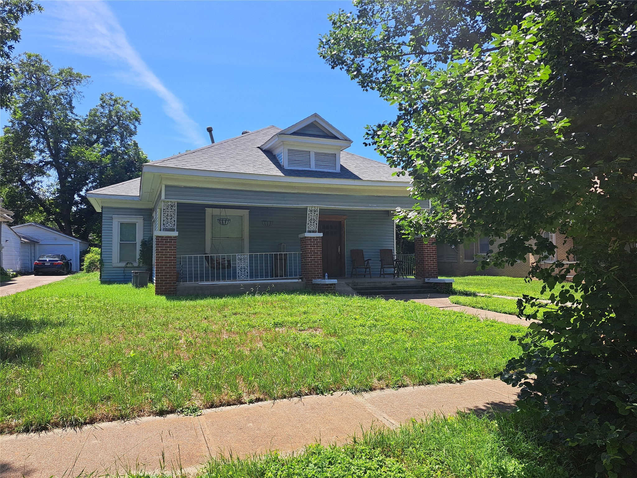 View of front of home featuring covered porch, a front lawn, and roof with shingles